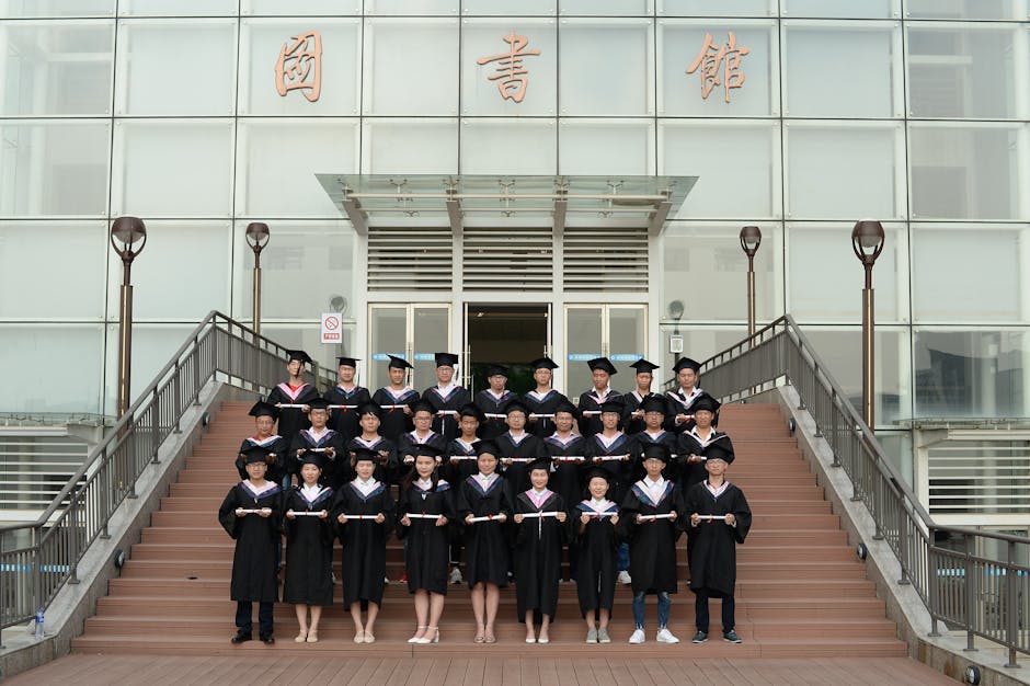 Group of graduates in academic dress standing on stairs, celebrating their achievement.
