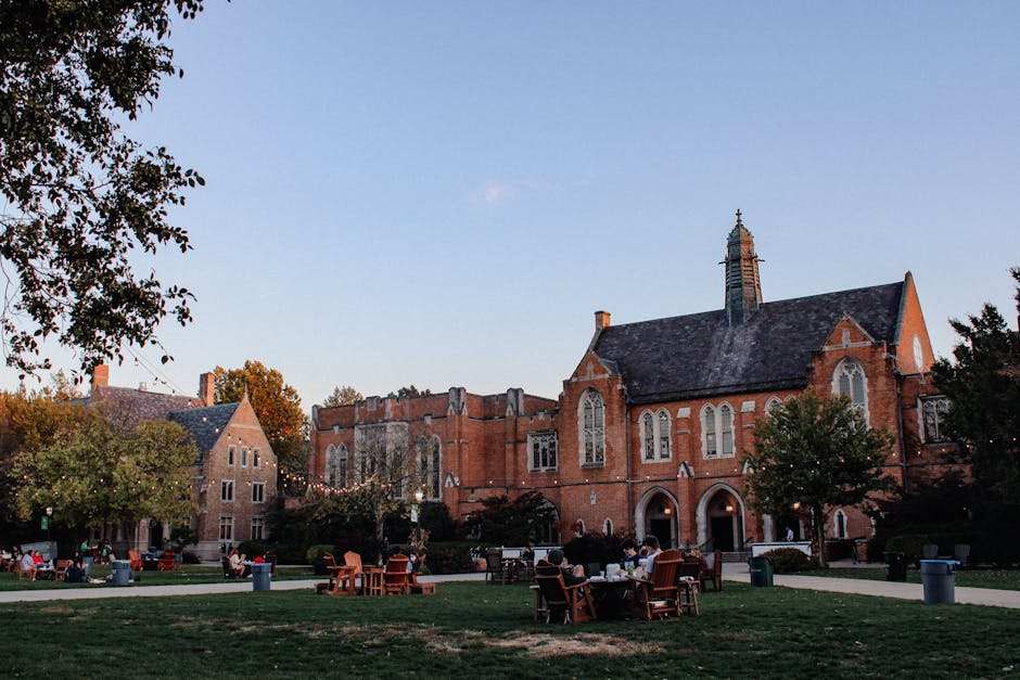 Scenic view of Notre Dame campus with Gothic-style buildings and students on a green field.